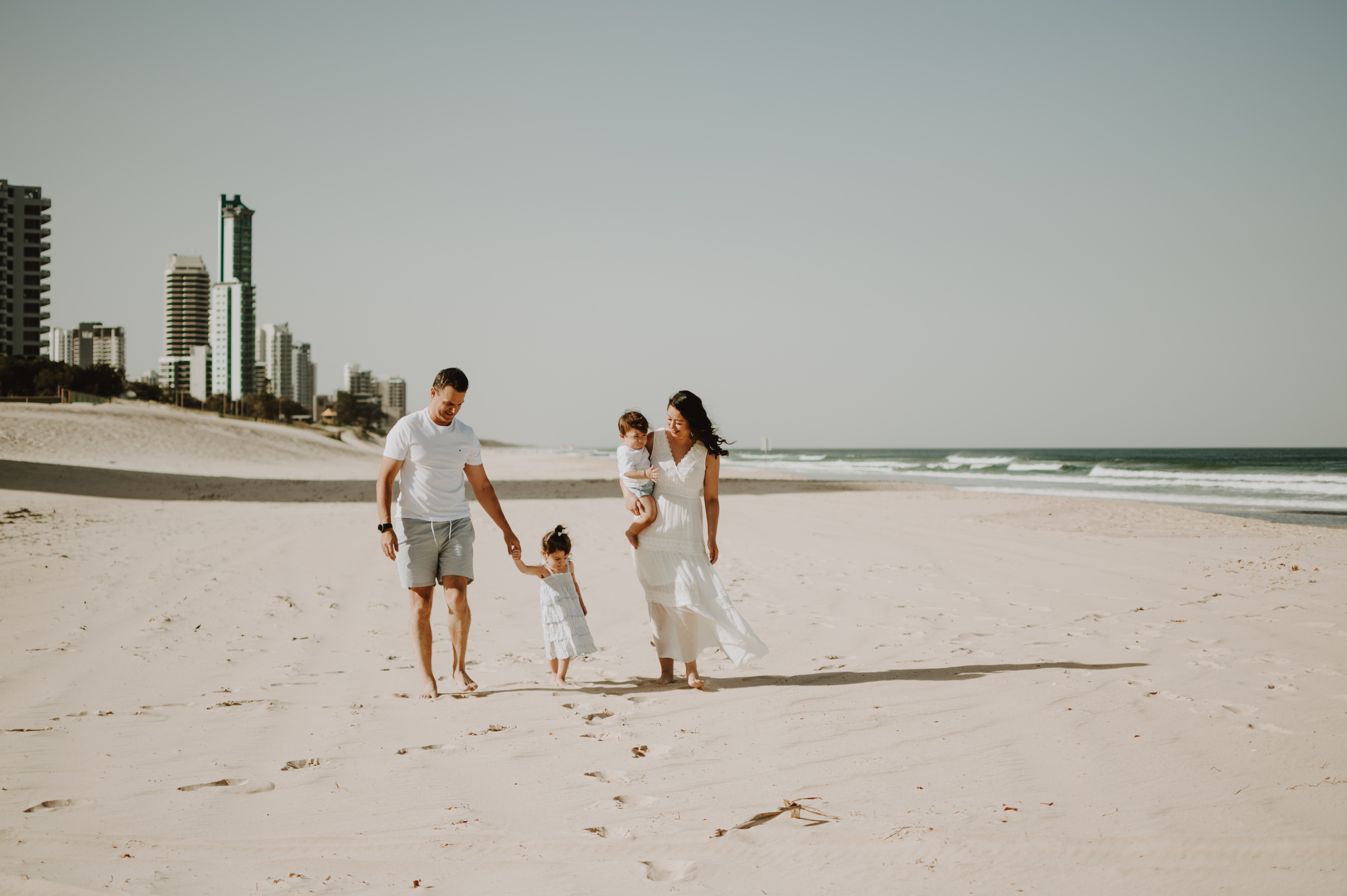 A family walks on Surfers Paradise Beach in the Gold Coast on a sunny day.
