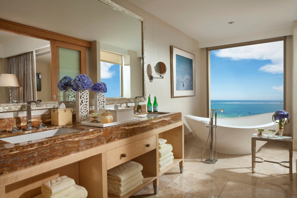 View from the bathroom of the Royal Suite at The Mulia, overlooking the turquoise ocean from the standalone bathtub