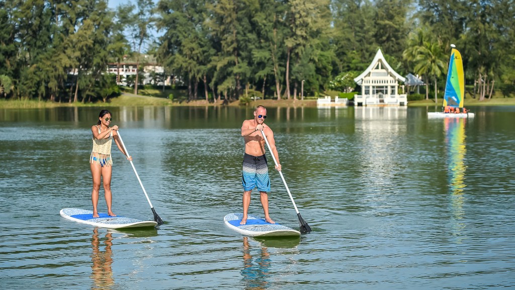 Two people enjoying a stand-up--paddle-board from Angsana Laguna Phuket, one of The Best Family Resorts in Phuket - Luxury Escapes 