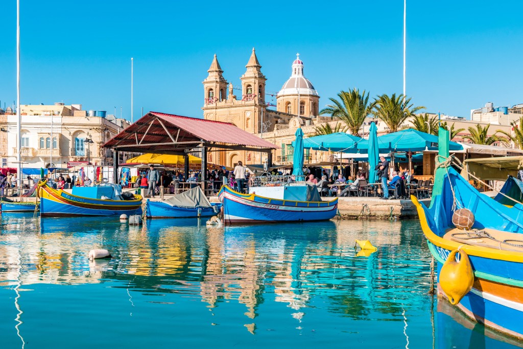 Boats moored at the pier at the Marsaxlokk fish market in Malta – Luxury Escapes