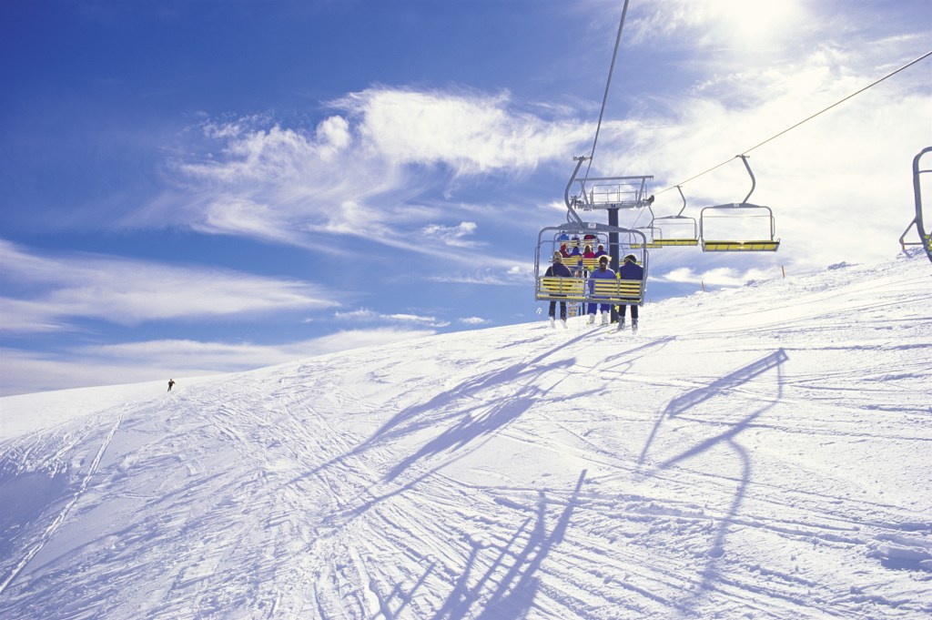 People enjoying the snow on Mount Hothan from above in chair lifts - Luxury Escapes