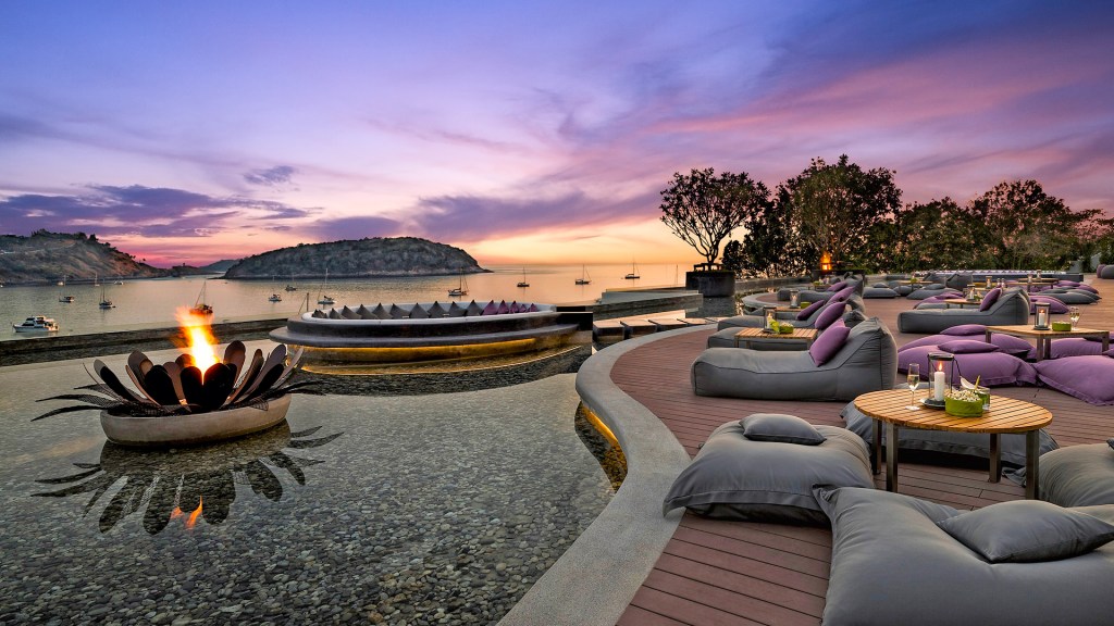Sunset over the water feature and firepit on the deck of Nai Harn resort, Nai Harn Bay, one of the best beach resorts in Phuket, Thailand.