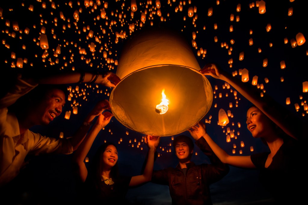 Letting go of a lantern at one of Chiang Mai, Thailand's best lantern festivals - Luxury Escapes