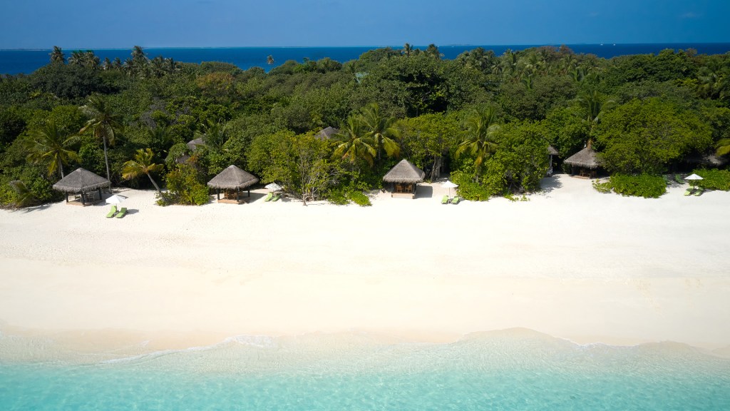 Iridescent blue waters lapping the golden sands at JA Manafaru - Luxury Escapes