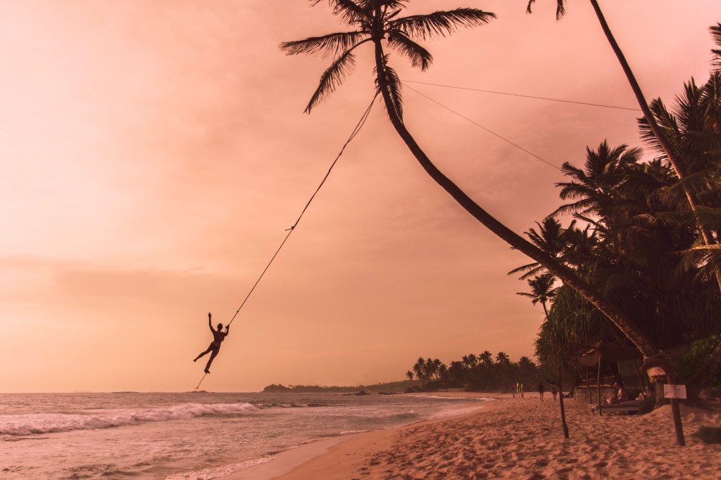 A person on a swing in the beach town of Unawatuna, one of Sri Lankas best beaches - Luxury Escapes 