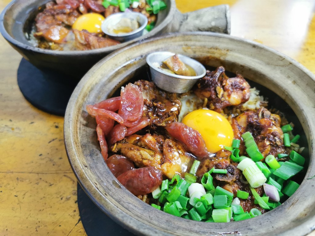 A full bowl of Cantonese food with an egg yolk, one of the best foods in Hong Kong - Luxury Escapes 