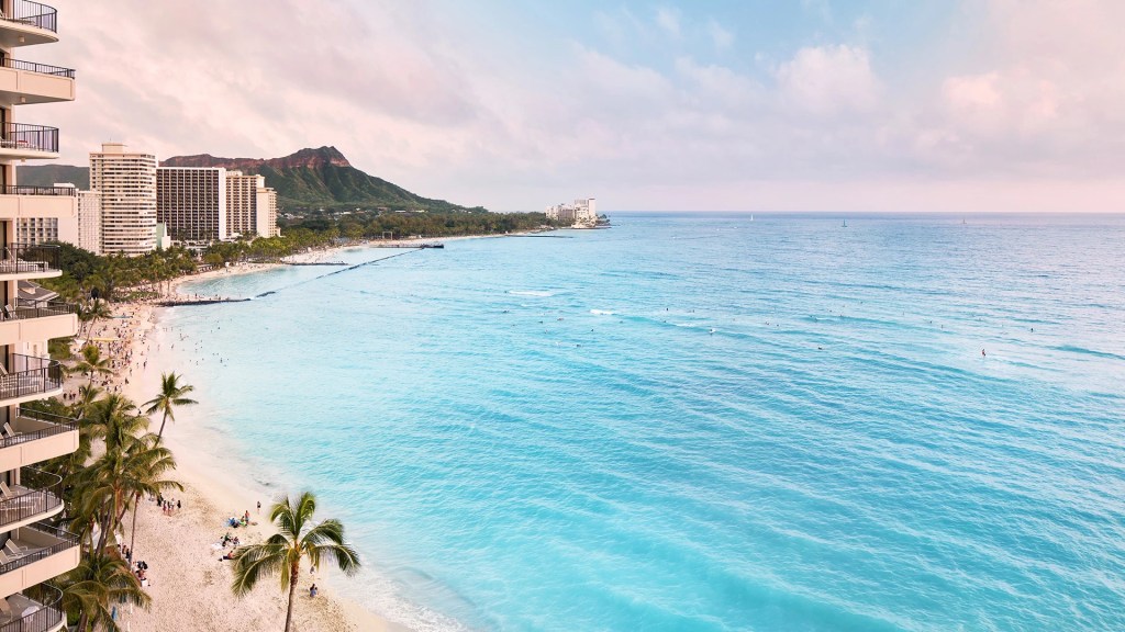 An aerial shot o the beach and landscape next to the Outrigger Waikiki Beach Resort in Hawaii, one of the best family friendly resorts - Luxury Escapes