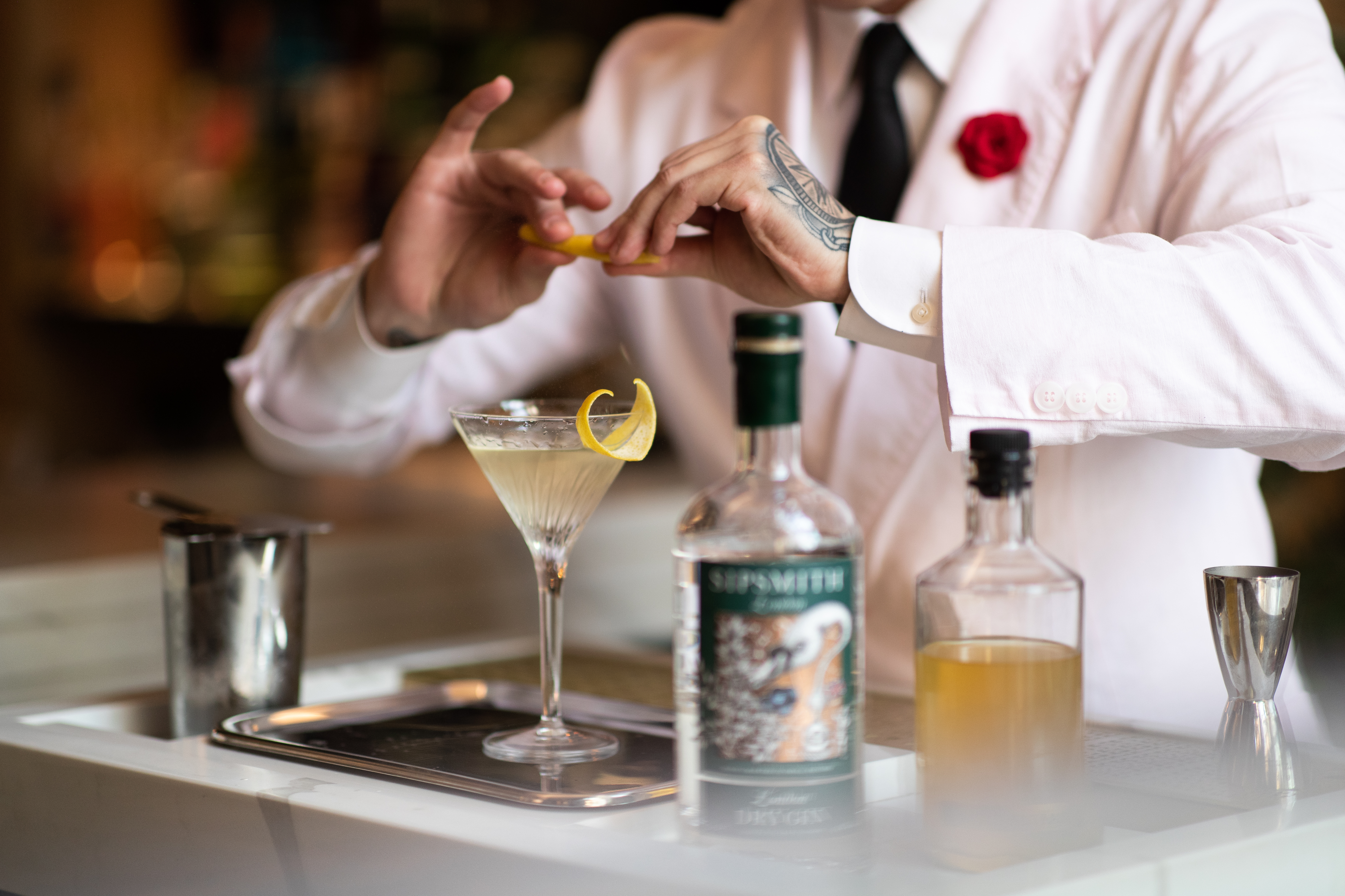 A bartender spritzes a lemon peel over a cocktail behind the bar at Maybe Sammy in The Rocks, one of Sydney's top 10 bars of 2023 - Luxury Escapes