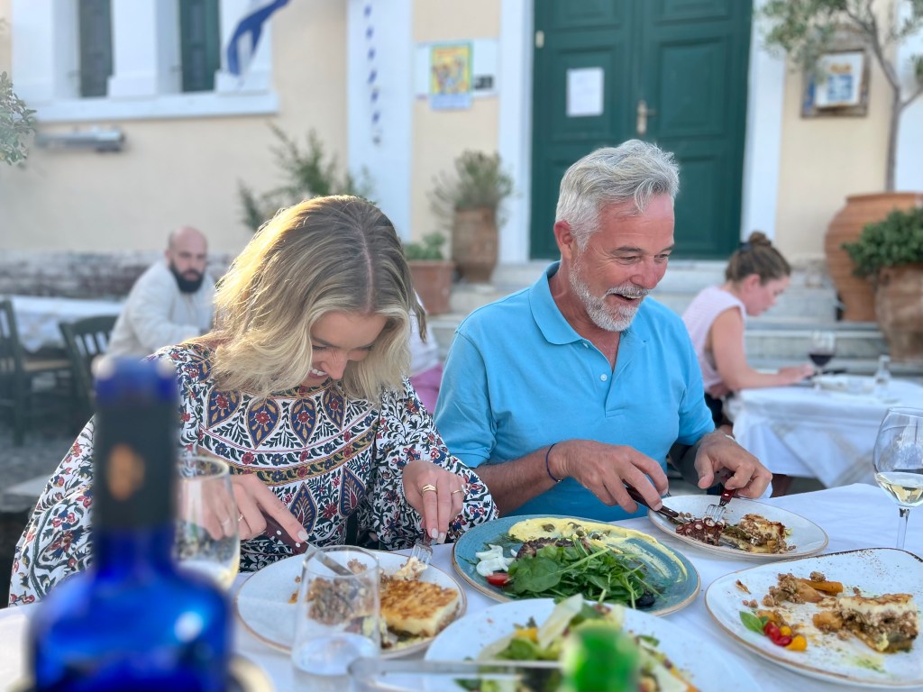 Holly and Cameron laugh while eating traditional Greek cuisine while touring through Greece - Luxury Escapes