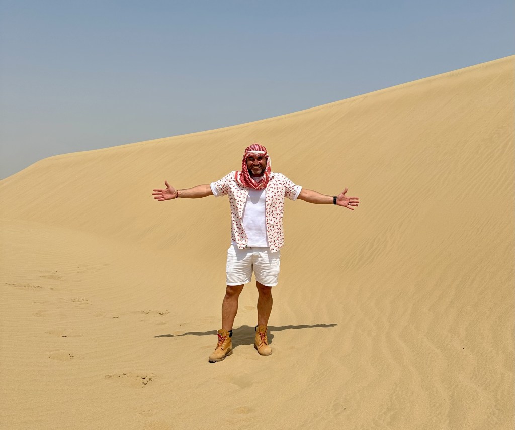 Chef Miguel Maestre, host of Luxury Escapes: The World's Best Holidays, posing on a sand dune in Dubai, one of the best things to do in Dubai - Luxury Escapes