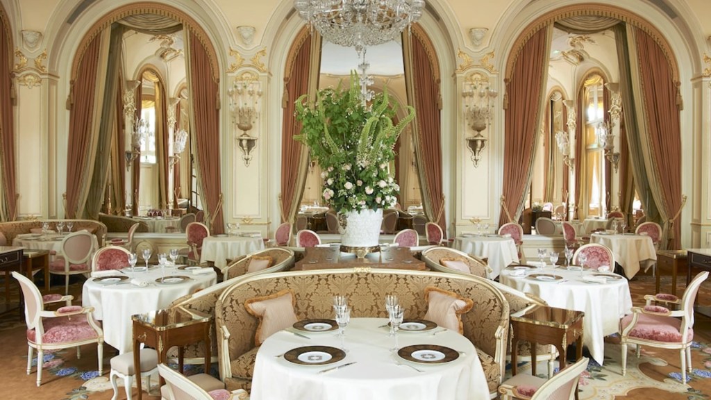A glamorous dining room with set tables and regal curtains within Ritz Paris, one of the most extraordinary heritage hotels - Luxury Escapes